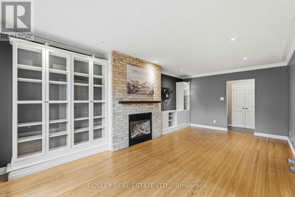 Living room with hardwood floors, brick fireplace, and built-in white shelving. - 3 Brian Avenue, St  Catharines