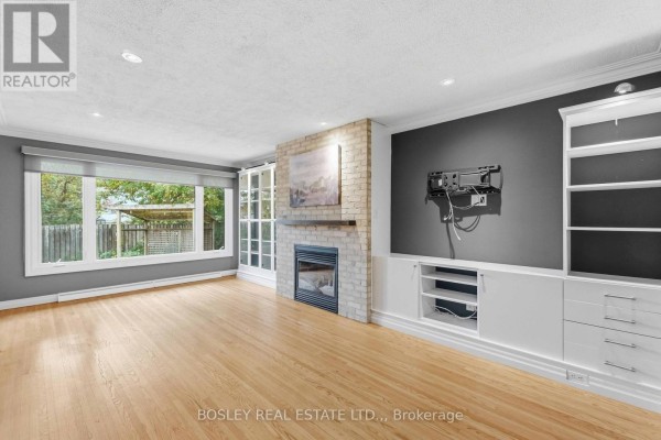 Living room with large windows, hardwood floors, brick fireplace, and built-in shelving. - 3 Brian Avenue, St  Catharines
