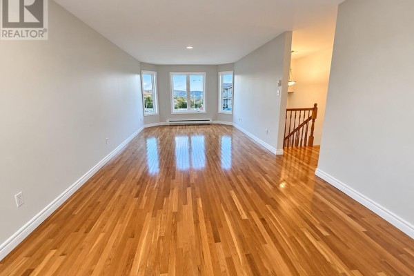 Living room with hardwood floors, beige walls, and bay windows overlooking a neighborhood. - 3 Burdell Place, St  John S