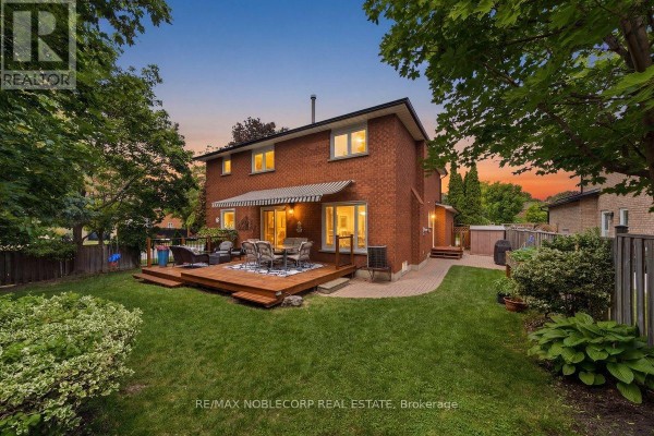 Rear view of a brick house with a wooden deck and patio overlooking a grassy backyard. - 3 Castlehill Road, Vaughan