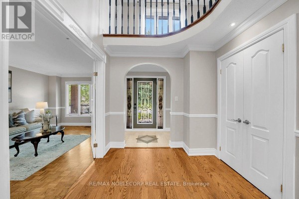Interior foyer with hardwood floors, white trim, double doors, and an arched doorway to the living room. - 3 Castlehill Road, Vaughan