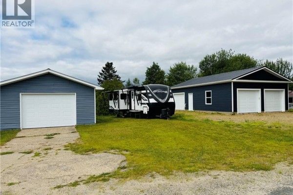 Three detached garages on a grassy lot, with an RV parked between two garages. - 3 Ch Manuel, Baie Sainte Anne
