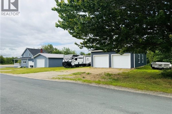 Distant view of blue house, garages and RV, partially obscured by a large tree. - 3 Ch Manuel, Baie Sainte Anne