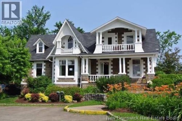 Front exterior of a stone and shingle home with balconies, porch, and landscaping. - 3 Cross Unit# E, Moncton