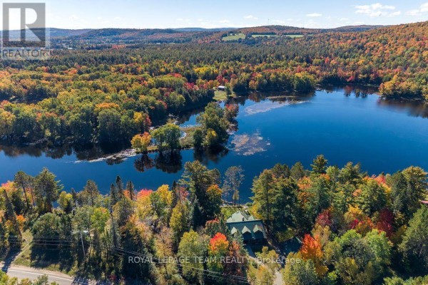 Aerial view of a log home nestled amongst colorful autumn trees beside a calm blue lake. - 3 Dam Road, Brudenell, Lyndoch And Raglan