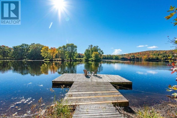 Wooden dock with two chairs on a calm lake surrounded by trees in autumn. - 3 Dam Road, Brudenell, Lyndoch And Raglan