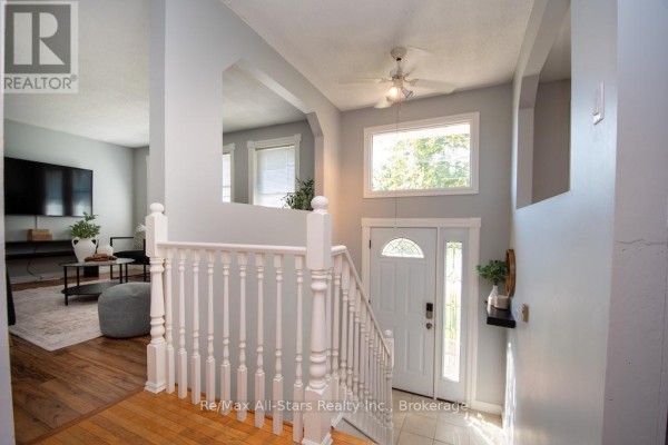 View from living room looking towards the foyer with white banisters and a large window. - 4 Daniel Court, Kawartha Lakes