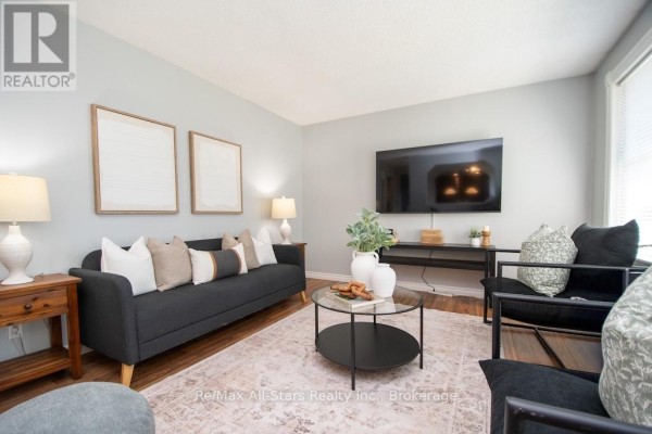 Living room with a dark grey sofa, black chairs, a television, and a coffee table. - 4 Daniel Court, Kawartha Lakes