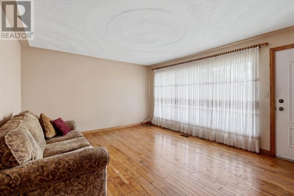 Living room with hardwood floors, a sofa, and large curtains looking towards the entrance. - 3 Dawson Ave, Sault Ste  Marie
