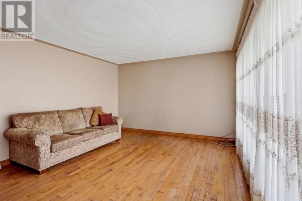 Living room with hardwood floors, a sofa, and large curtains. - 3 Dawson Ave, Sault Ste  Marie
