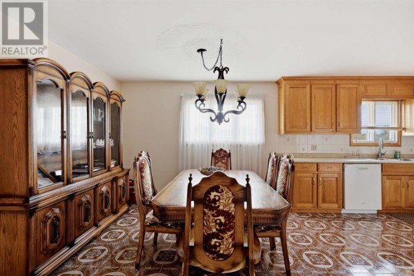 Dining room with a wooden table and chairs, a china cabinet, and kitchen cabinets. - 3 Dawson Ave, Sault Ste  Marie