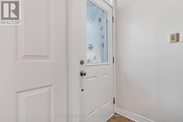 Interior view of white front door with frosted glass panel and beige flooring. - 3 De Jong Street, Toronto