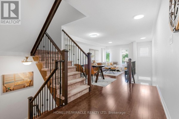 Open concept living and dining area with hardwood floors, stairs, and modern furniture. - 3 De Jong Street, Toronto