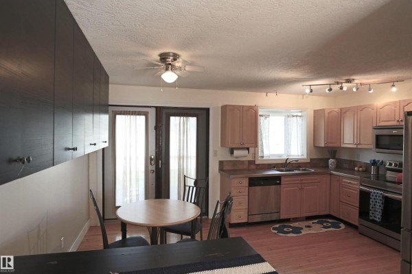 Kitchen and dining area with light wood cabinets, stainless steel appliances, and glass double doors. - 3 Dorchester Rd, Spruce Grove