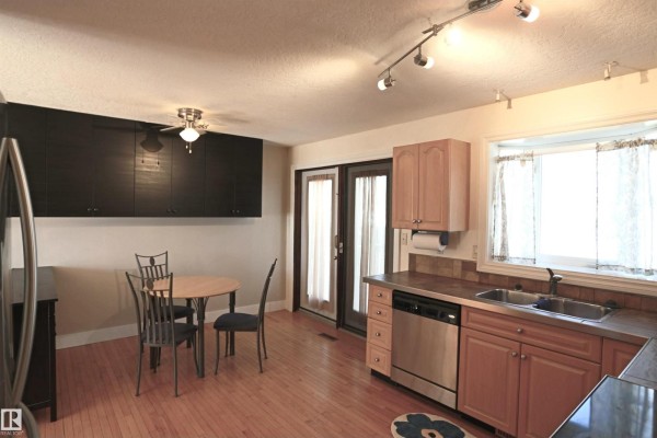 Kitchen view showing light wood cabinets, stainless steel appliances, and a circular dining table. - 3 Dorchester Rd, Spruce Grove