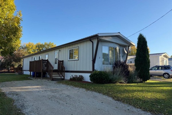 Side view of a manufactured home with a gravel driveway and grass. - 3 Dray Place Sw, Altona