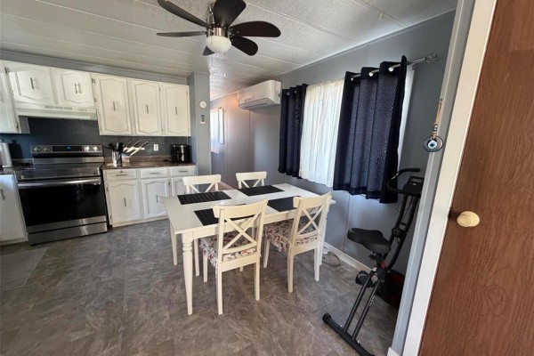 Kitchen and dining area with white table, chairs, and white cabinets. - 3 Dray Place Sw, Altona