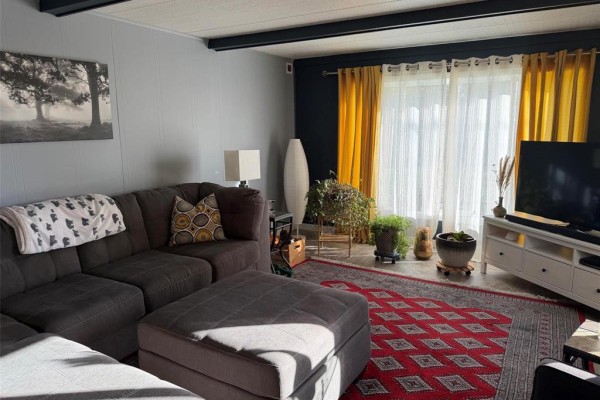 Living room with a grey sectional sofa, ottoman, and yellow curtains. - 3 Dray Place Sw, Altona