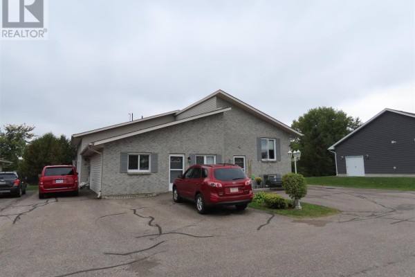 Side view of a grey brick multi-family building with a red SUV parked in the driveway. - 3 Elmwood Ave, Sault Ste  Marie