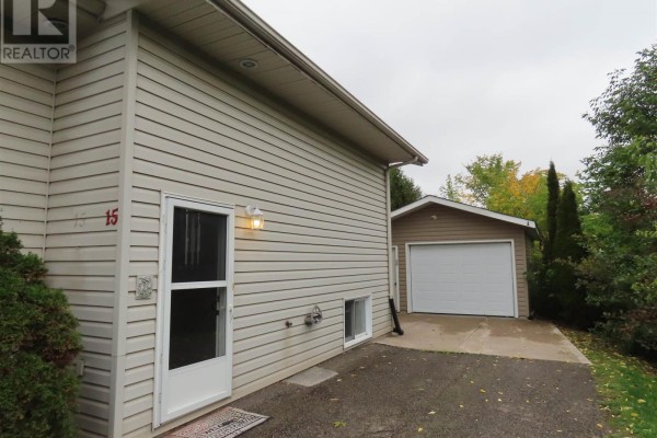 Side entrance of a beige siding unit at 15 Elmwood Ave with a detached single garage. - 3 Elmwood Ave, Sault Ste  Marie