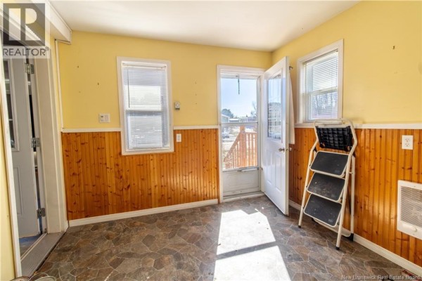 Interior view of a room with yellow walls, stone flooring, and a door leading outside. - 3 Fifth Street, Sussex Corner