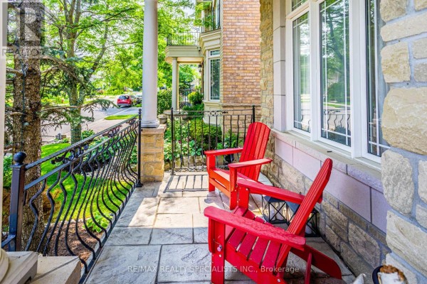 A porch with two red Adirondack chairs and stone tile flooring, overlooking a tree-lined street. - 3 Fogerty Street, Brampton