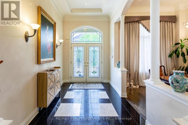 Interior view of the home's foyer with a console table, artwork, and double glass doors. - 3 Fogerty Street, Brampton