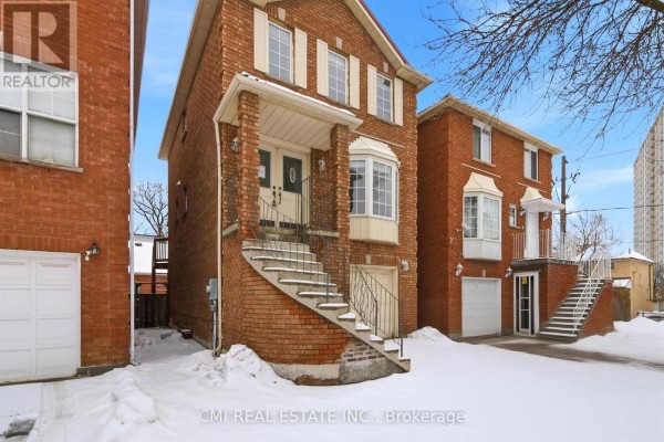 Close-up of the brick exterior of a townhouse, showing the central entrance, stairs, and garage door. - 3 Forest Point Drive, Toronto