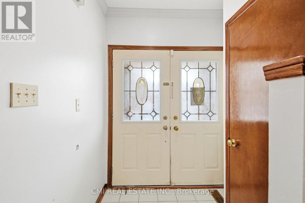 Interior view of a hallway with a white wall, beige double doors with frosted glass panels, and a wooden door. - 3 Forest Point Drive, Toronto