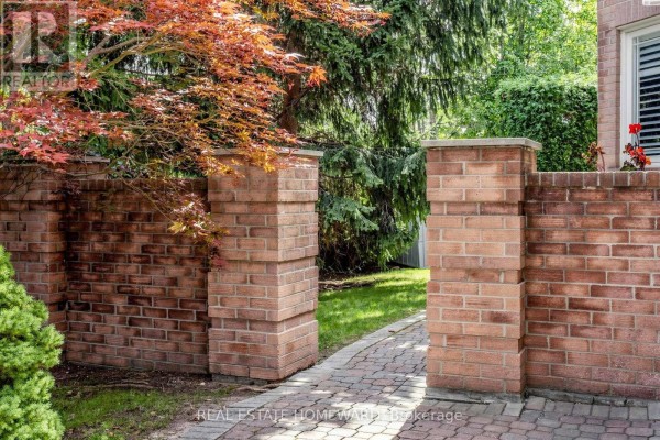A brick wall with two supporting pillars and a paved walkway leading to a garden area. - 3 Green Acres Road, Vaughan