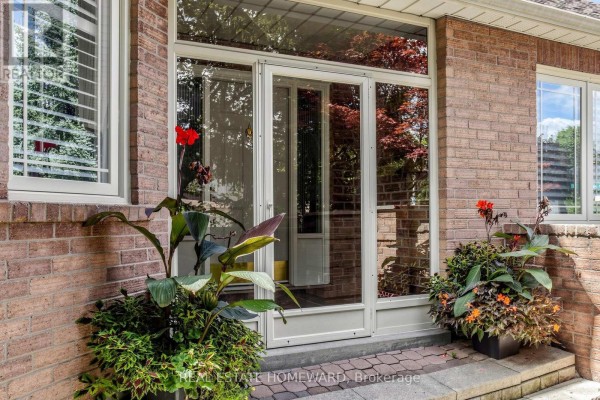 Front entrance of a brick house with a glass door, large windows, and potted plants on the steps. - 3 Green Acres Road, Vaughan