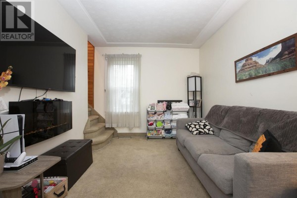 Living room with TV, sofa, storage, and stairs - 3 Henrietta Ave Sault Ste Marie