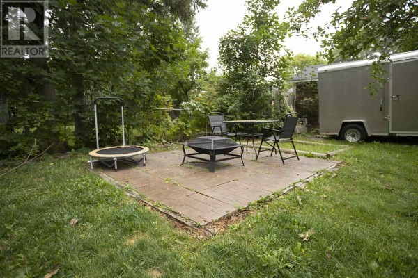 Backyard patio with fire pit, dining set, trampoline, and trailer - 3 Henrietta Ave Sault Ste Marie