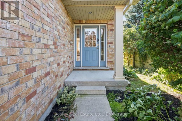 Front porch entrance with a blue door, surrounded by brick walls and green foliage. - 3 Hunt Street, Guelph