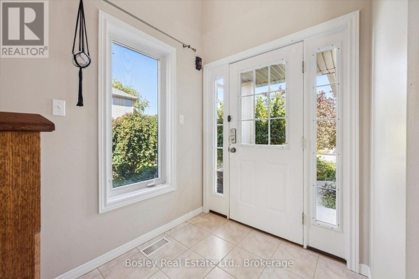 Interior entryway with a beige tiled floor, white door with glass panels, and a window to the outside. - 3 Hunt Street, Guelph