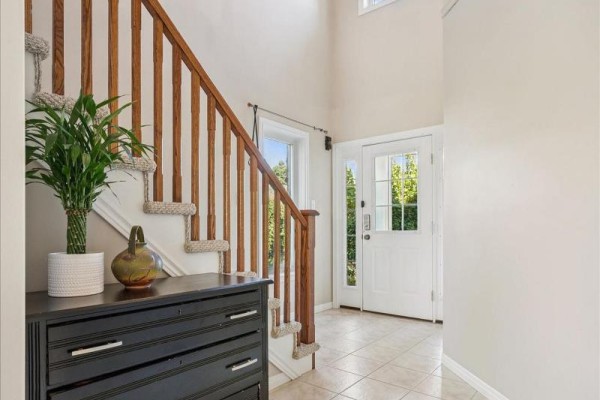 Foyer with beige tiles, a dark dresser, a staircase with wooden railing and beige carpeted steps. - 3 Hunt Street, Guelph