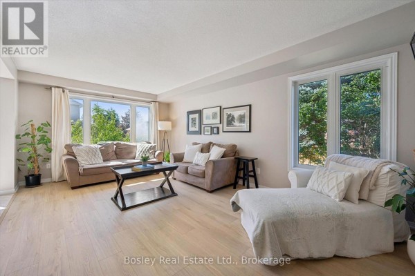 Living room with light wood floors, two brown sofas, a white chaise lounge, and large windows. - 3 Hunt Street, Guelph