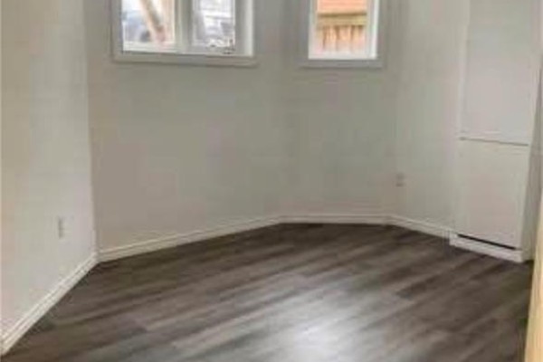 Empty room with gray wood-look flooring, white walls, and two small windows. - 3 Innswood Place Unit# Lower, Hamilton