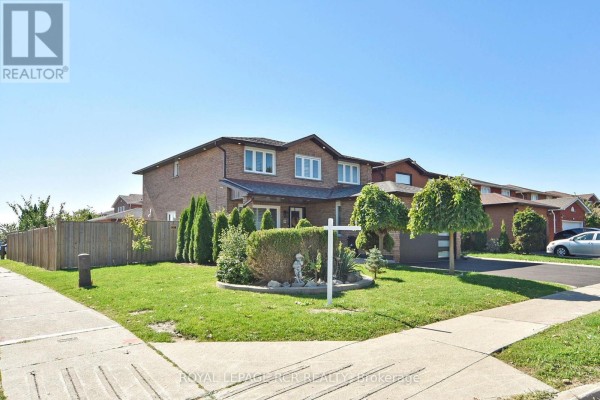 Side exterior view of the brick house with a green lawn, garden beds, and fence. - 3 Jackman Crescent, Vaughan