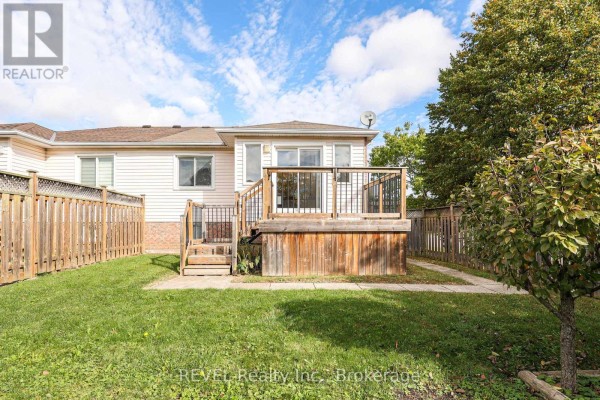 Backyard view of a wooden deck and fenced yard with a mature tree. - 3 Jackson Court W, Welland