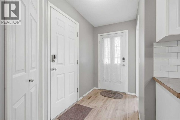 Interior entryway with light wood laminate flooring, white doors, and a pantry closet. - 3 Janko Close, Red Deer