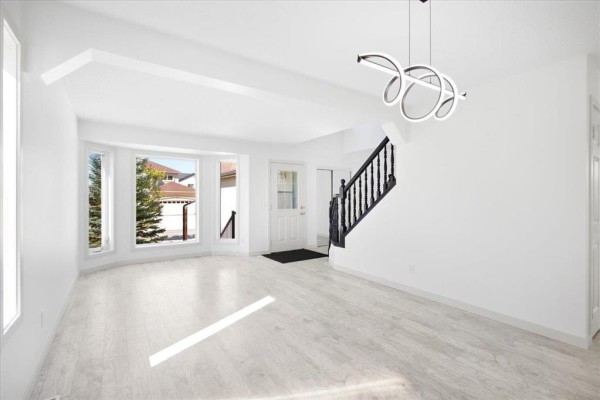 Living room with a white couch, glass coffee table, black armchairs, and a black staircase. - 3 Kingfisher Crescent, Winnipeg