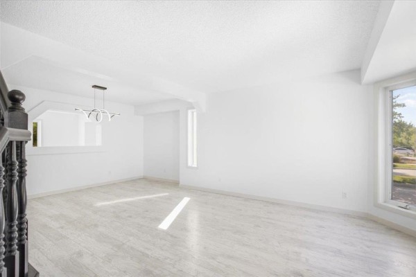 Bright living room with a large bay window, white couch, and light wood floors. - 3 Kingfisher Crescent, Winnipeg