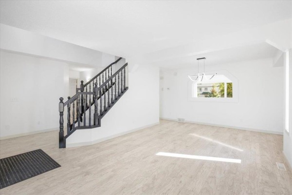 Living and dining area with white furniture, a black dining table, and a modern chandelier. - 3 Kingfisher Crescent, Winnipeg