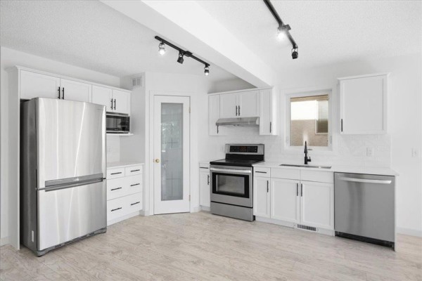 Dining area with a black rectangular table, white chairs, and a contemporary abstract art piece. - 3 Kingfisher Crescent, Winnipeg