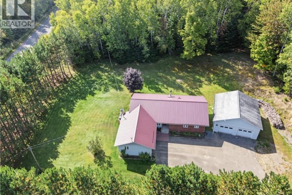Aerial view of a residential property with a ranch house, detached garage, and surrounding woodland, featuring a long driveway. - 3 Maple Street, Lower Woodstock