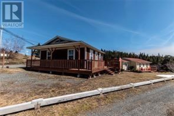 Red-sided house with a wooden deck and porch, set against a bright blue sky. - 3 Marshall’s Hill, Trinity East