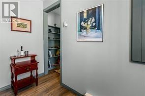 Hallway with grey walls, hardwood floors, a red side table, and framed artwork. - 3 Marshall’s Hill, Trinity East