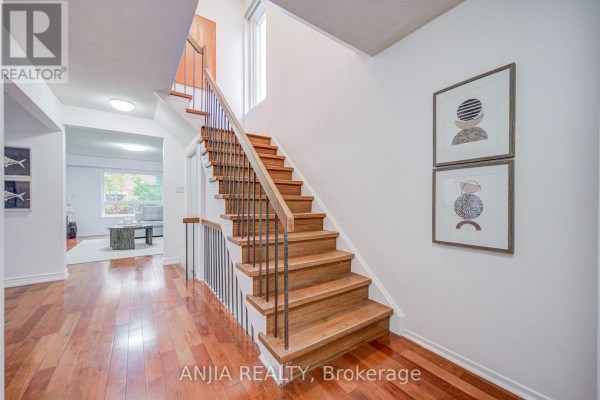 Interior staircase with wooden steps, white walls, and modern art. - 3 Mossbrook Crescent, Toronto