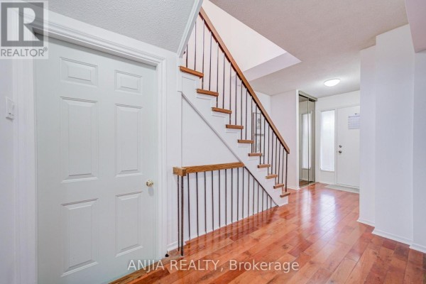 View of the foyer with wood flooring, staircase, and white doors. - 3 Mossbrook Crescent, Toronto